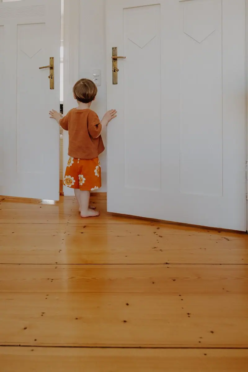 Kind steht zwischen den Türen beim Familienshooting in schöner Altbauwohnung in Darmstadt