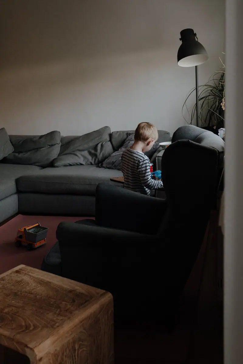 Kind spielt versunken im Wohnzimmer beim entspannten Familienshooting zu Hause