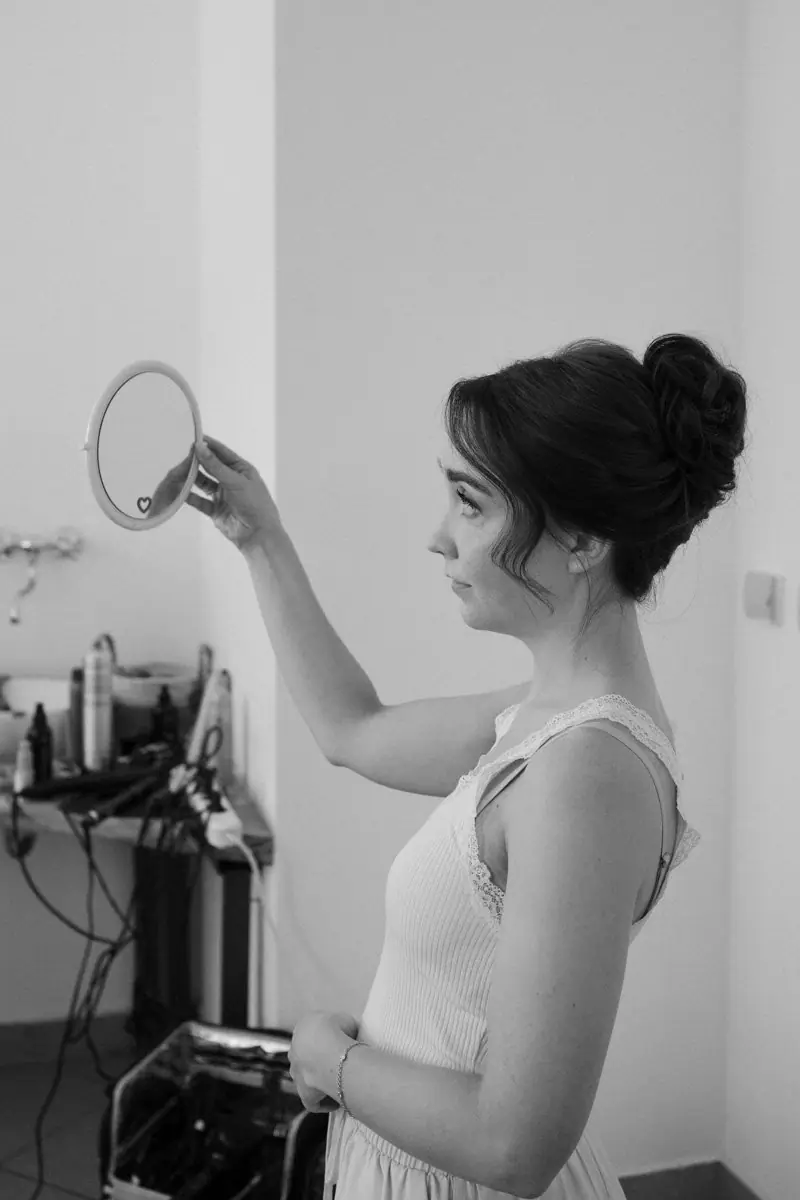 Braut steckt sich die Haare vor dem Spiegel