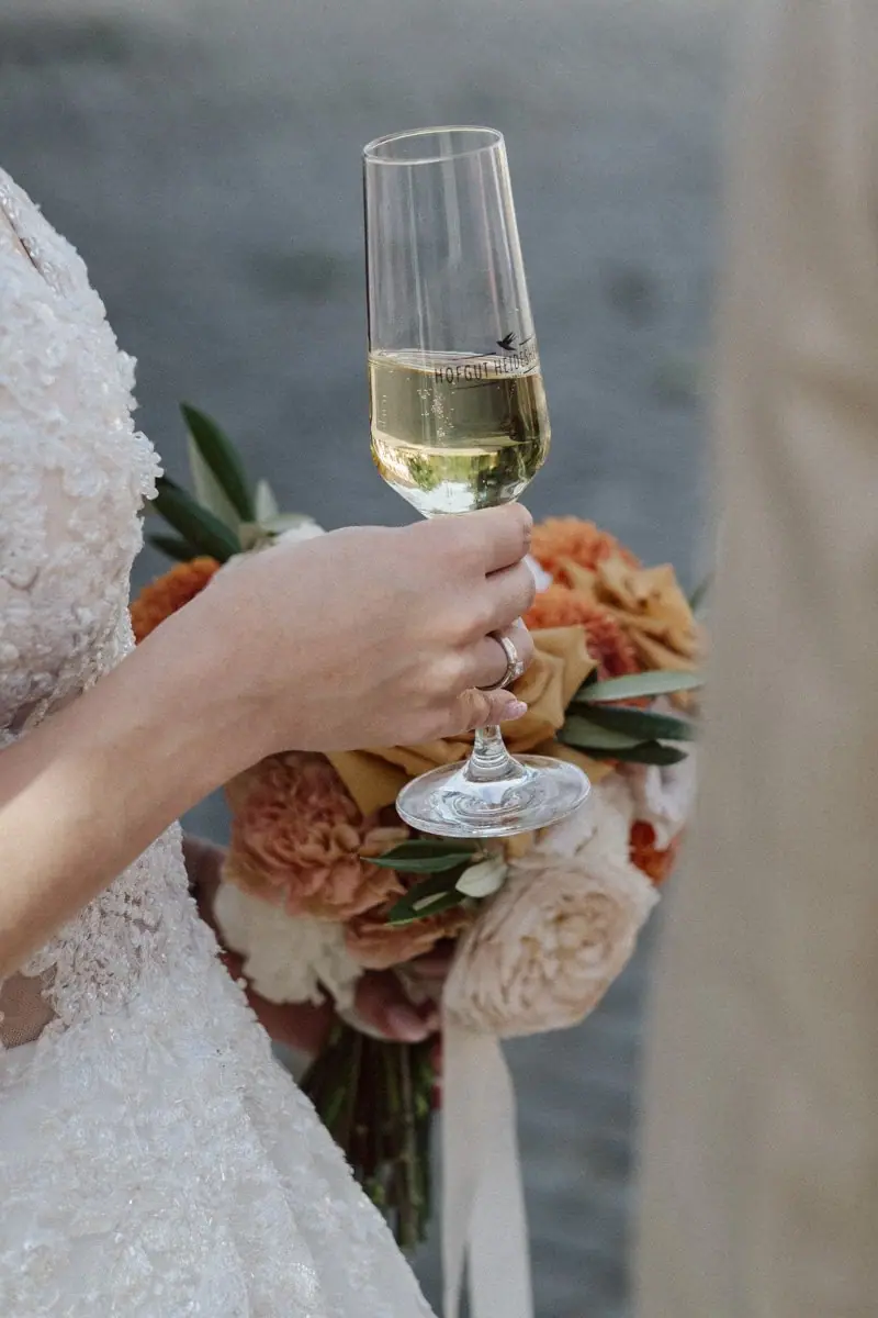 Hand mit Sektglas und Strauß
