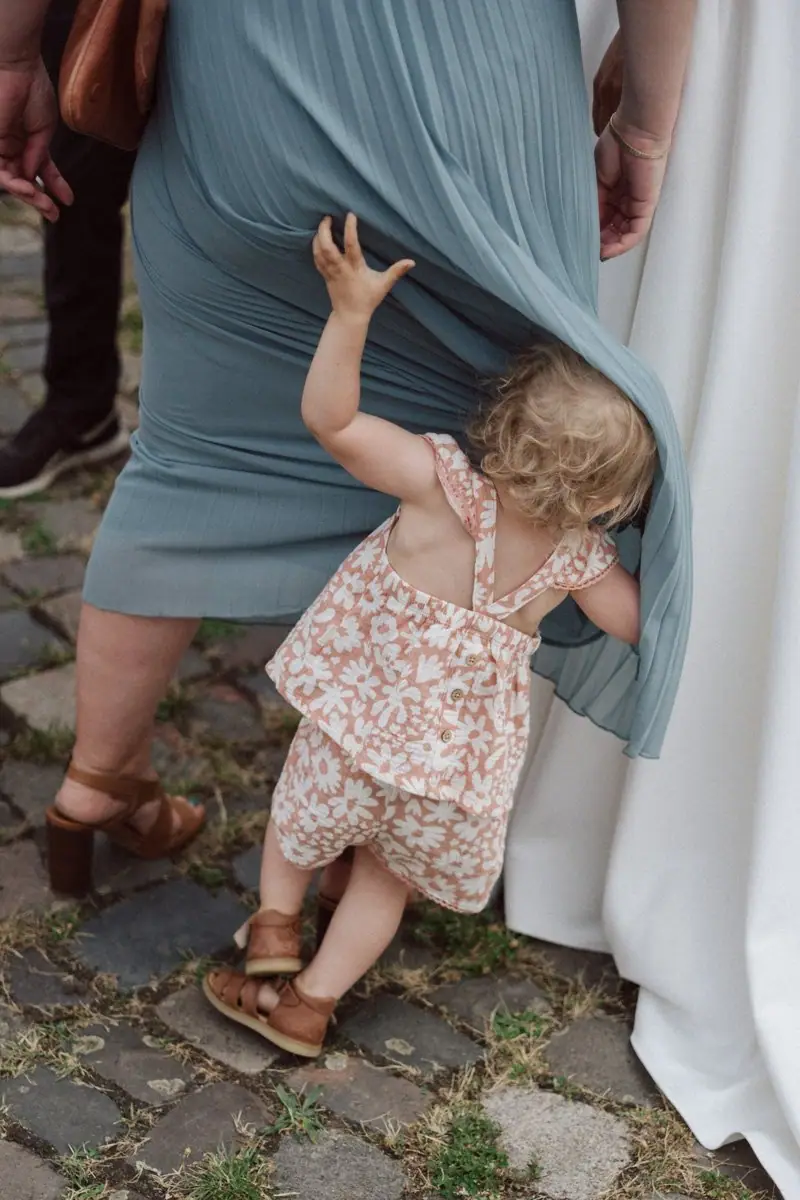 Kind versteckt sich im Kleid der Mutter