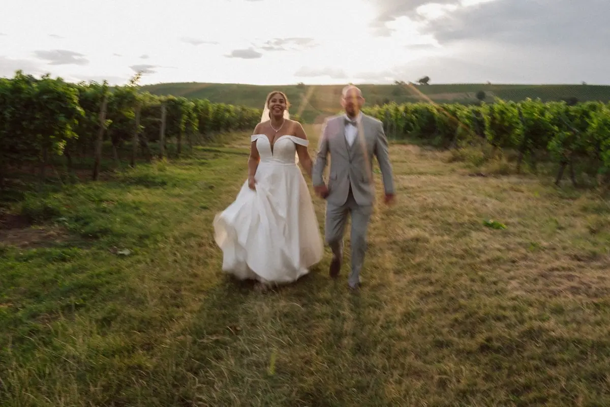 Brautpaar läuft durch den Weinberg im Abendlicht
