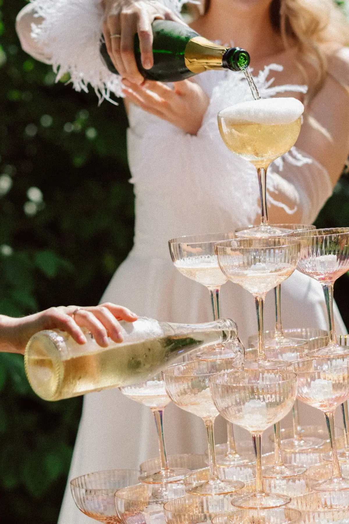 Braut gießt Sekt in eine Glas-Pyramide