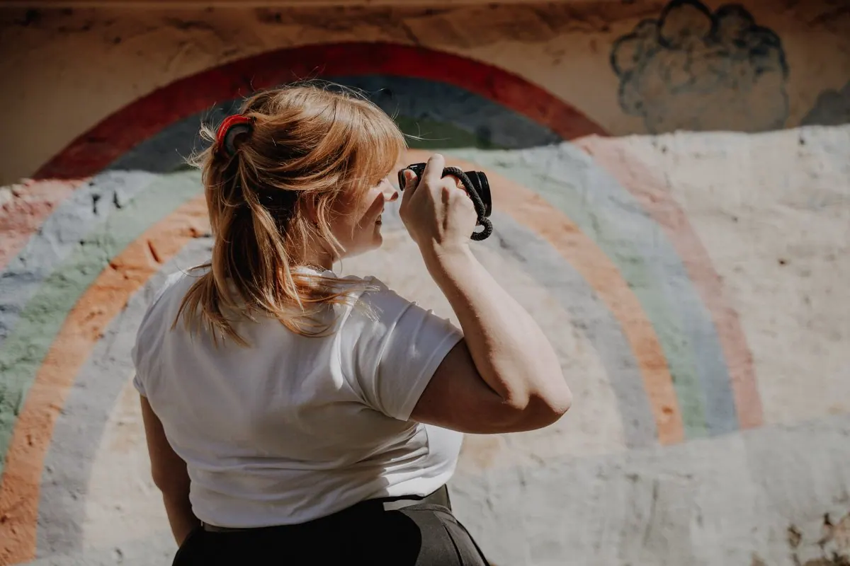 Paulina Ritter fotografiert vor einem Regenbogen-Wandbild